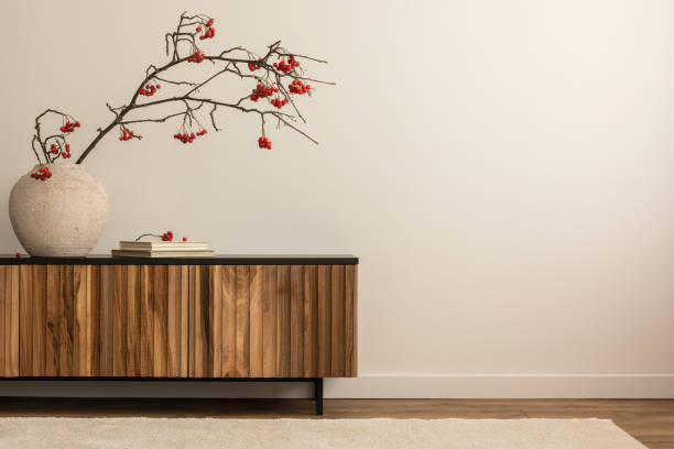 ästhetische komposition des japanischen wohnzimmers interieur mit kopierraum, holzsideboard, runder vase mit roter eberesche, büchern, hellem teppich, weißer wand und persönlichen accessoires. wohnkultur. schablone. - curtain home decorating living room showcase interior stock-fotos und bilder