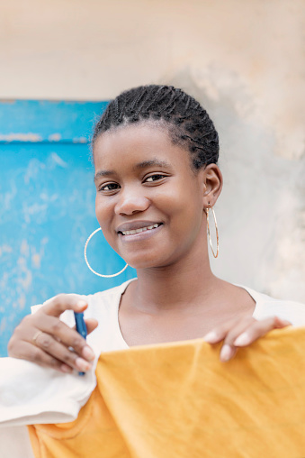 Young Afro beauty hanging her laundry, cheerful expression, braided hair, 19 years old, photo