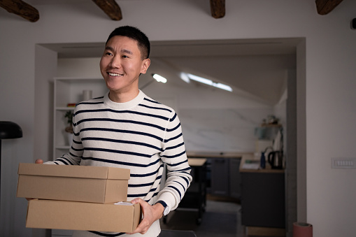 Happy Asian freelance worker carrying packages ready for shipping in the office.