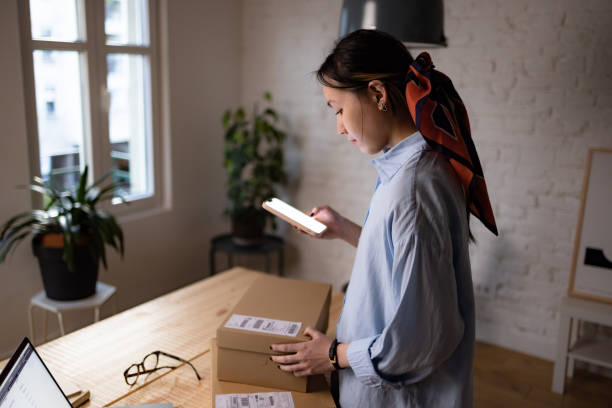 istock Asian woman scanning bar code of a package at home office. 1459633263