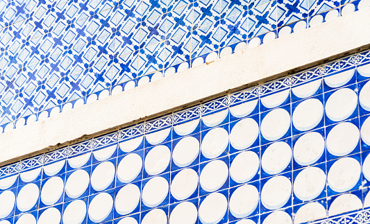 Different tile designs with blue and white patterns on the exterior wall of a building in the Baixa district of central Lisbon, Portugal.