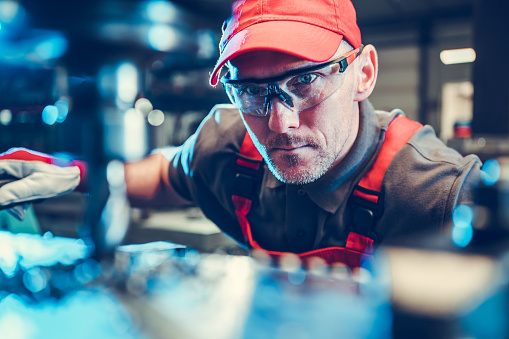 Caucasian Milling or Lathe Machine Operator in His 40s Wearing Safety Glasses. Metalworking Industry Theme.