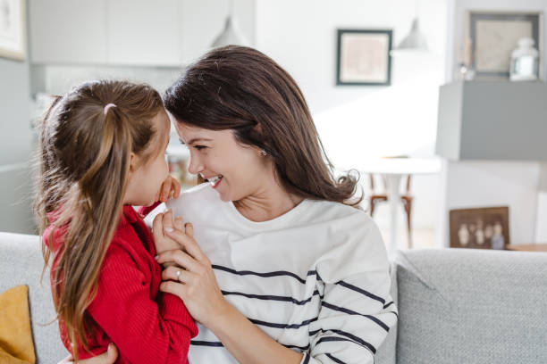 istock Mother and daughter cuddling while sitting on sofa 1459635513