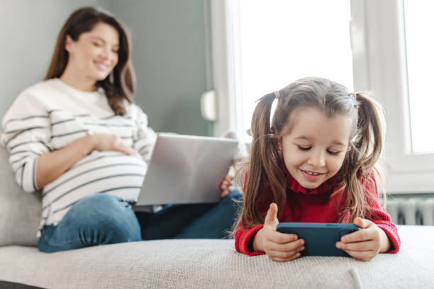 istock Pregnant mother and her daughter using wireless technology at home 1459635720
