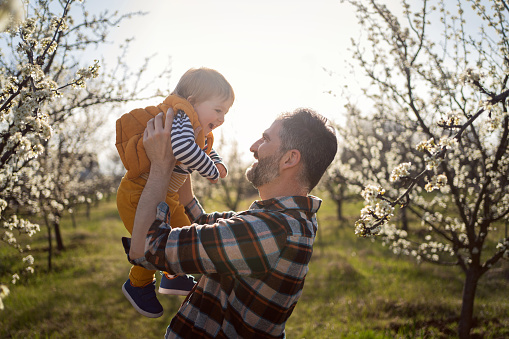 Father and son in a blooming orchard in spring.