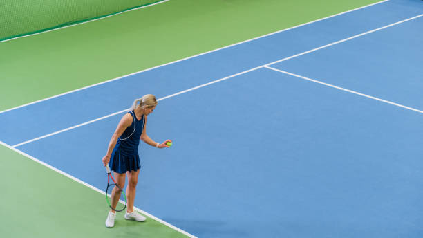 Female Tennis Player Preparing for Hitting a Ball with a Racquet During Championship Match. Professional Woman Athlete About to Strike. World Sports Tournament. High Angle Wide Shot Photo. Female Tennis Player Preparing for Hitting a Ball with a Racquet During Championship Match. Professional Woman Athlete About to Strike. World Sports Tournament. High Angle Wide Shot Photo. championships stock pictures, royalty-free photos & images