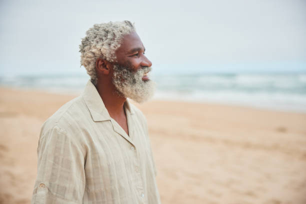 istock Smiling mature man standing on a beach and looking out at the ocean 1459652761
