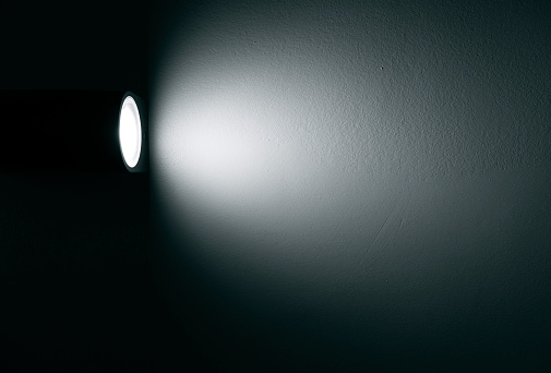 Spotlight, lamp with beam of light on the wall in dark room