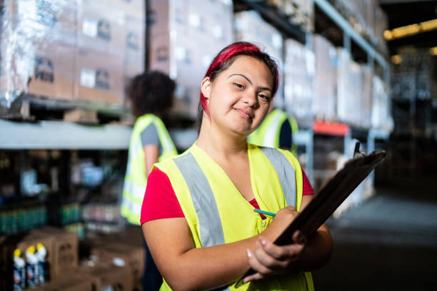Portrait of a disabled young woman holding a clipboard in a warehouse Portrait of a disabled young woman holding a clipboard in a warehouse developmental disability diversity stock pictures, royalty-free photos & images