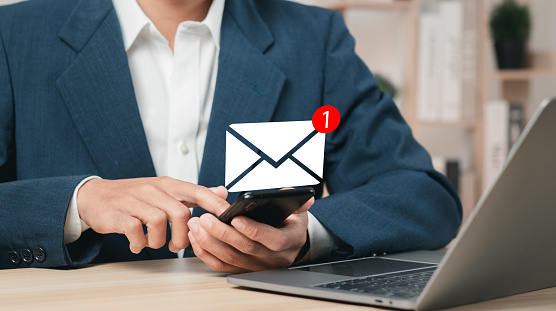 Businessman using smartphone and touching email icon with notification. Online communication concept.