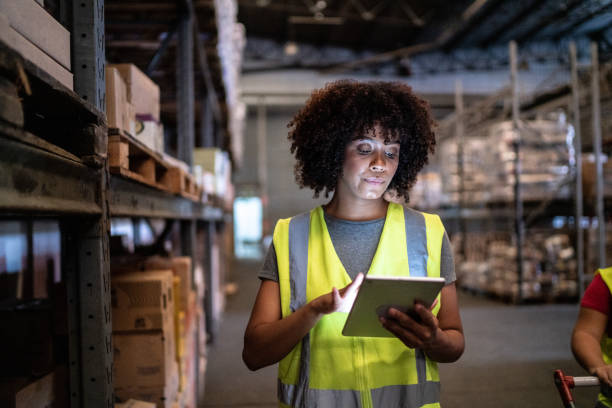 junge frau, die das digitale tablet in einem lager benutzt - warehouse worker stock-fotos und bilder