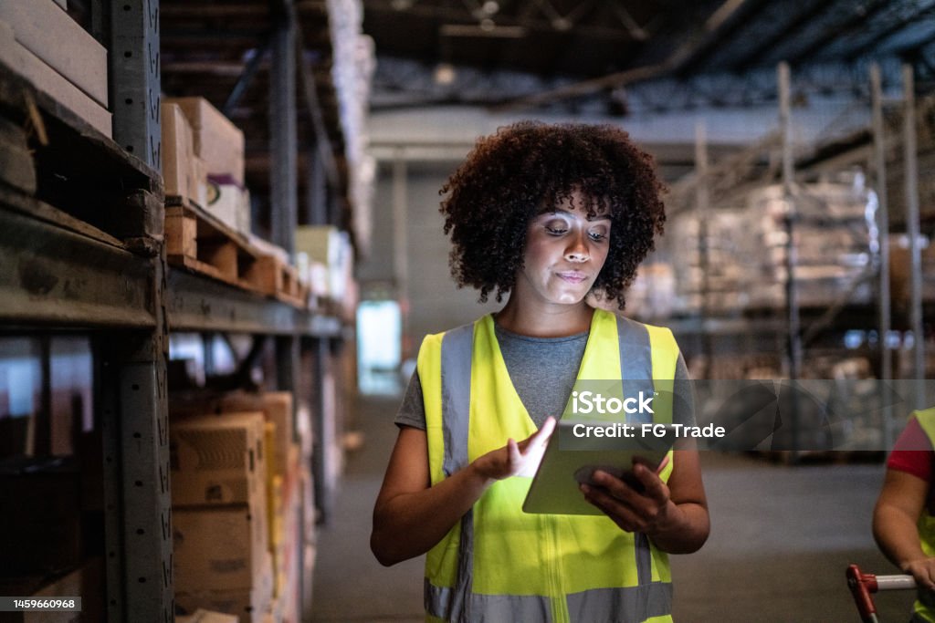 Young woman using the digital tablet in a warehouse Warehouse Stock Photo