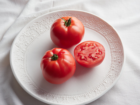 fresh whole and halved tomatoes on a white plate