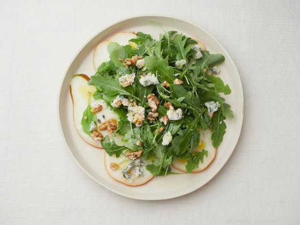 top view isolated plate of salad with arugula, pear, blue cheese and walnuts