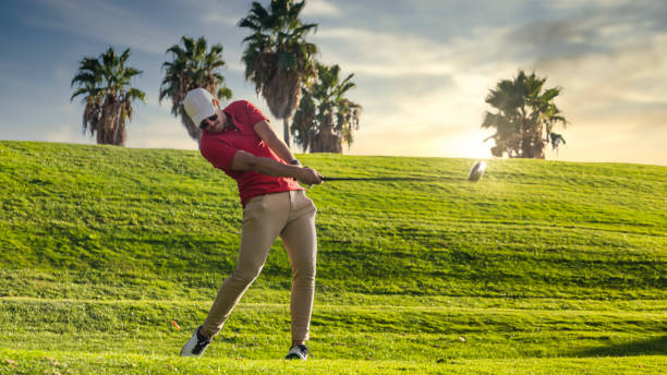 golfista che esce per una passeggiata su un campo da golf al tramonto. golfista che tiene gli occhi a terra dopo un lungo viaggio. copia spazio e bersaglio mobile. golfista con il cappello - golf playing teeing off men foto e immagini stock