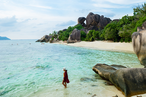 Young woman at Anse Source d'Argent beach La Digue Seychelles Islands, white tropical beach with granite boulders.