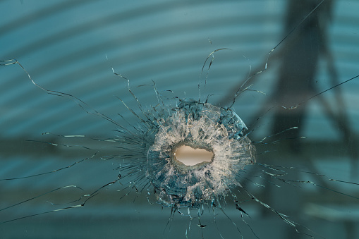bullet hole in glass - authentic shot - closeup isolated on white