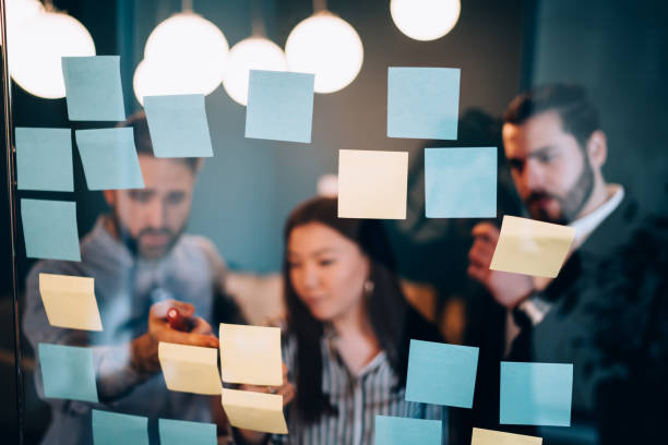 istock Group of coworkers using sticky notes on glass wall 1459665245