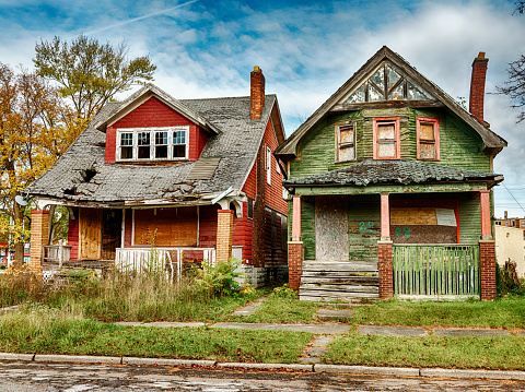 An abandoned house with boarded-up windows and rotting crumbling walls