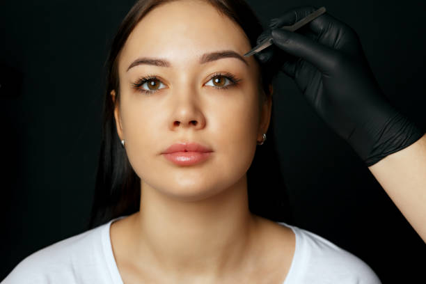 istock Cosmetician correcting woman's eyebrows with a tweezers 1459673229