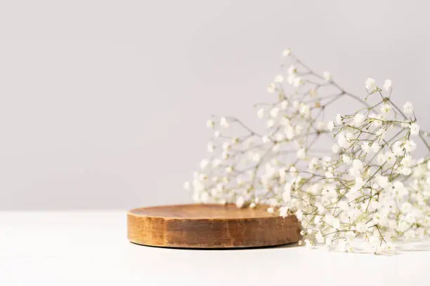 Photo of Beauty cosmetic product presentation scene made with a wooden plate and wild flowers. Summer mood background. Front view.