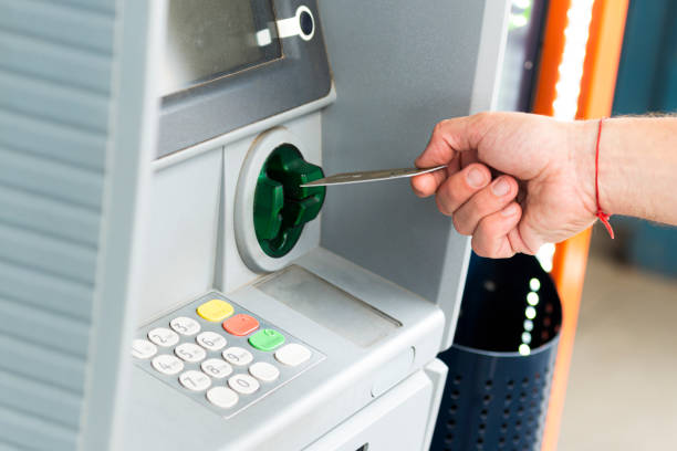 main humaine insérant une carte de crédit dans un guichet automatique - guichet automatique de banque photos et images de collection