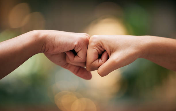 fist bump, friends and hands together for welcome with support, diversity and partnership collaboration. bokeh background, racism and friendship goal welcome greeting collaboration outdoor with bokeh - respect stockfoto's en -beelden