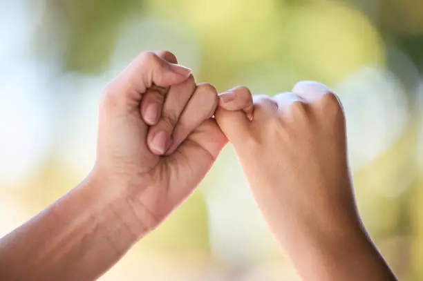 Photo of People, promise and fingers for support, trust and love connection in nature outdoors. Closeup, hands and couple of friends link little finger for hope, respect and commitment, kindness and agreement