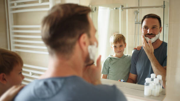 istock Son watching his father shaving in bathroom mirror 1459686551