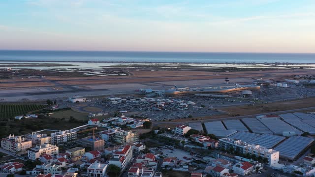 Aerial view of Portuguese Faro Airport, airplanes and runways against the sea. On the Sunset.