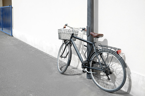 Vintage bicycle with basket locked to street post outdoors
