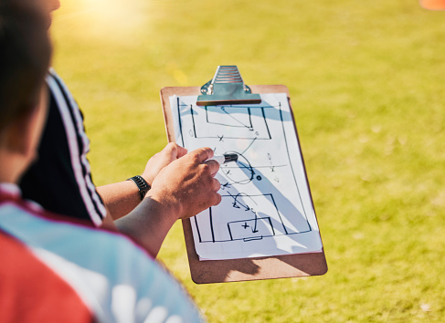 Clipboard, game planning and on field for soccer, sports and outdoor for competition with coach. Football group, strategy and communication for instructions, talking and paper for match day formation