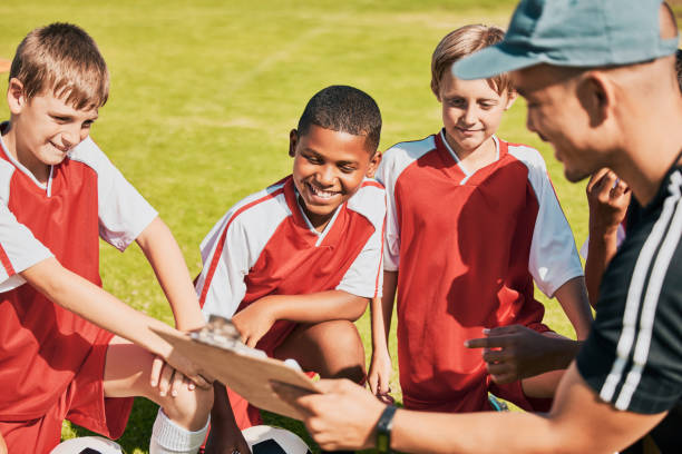 istock Soccer, children and coach with clipboard talking game plan, team training and formation on soccer field outdoor for fitness, competition and sport. Man talking to junior football group planning game 1459694337