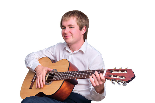 Portrait of a happy blond man with an acoustic guitar, isolated on a white background
