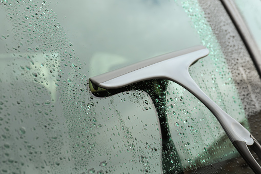 Wiping car window with drying blade outdoors, closeup
