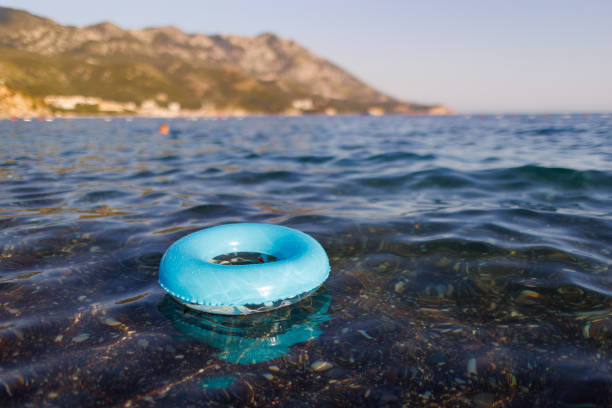 A small bright lost inflatable ring of blue color floats alone in the empty transparent blue Adriatic Sea in the evening