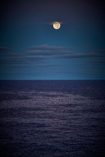 the full moon above the ocean.