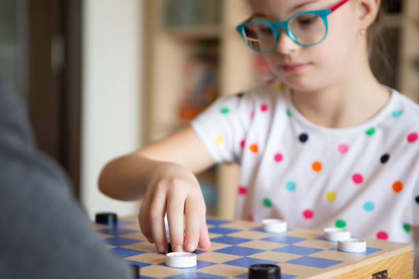 istock Girl with Down Syndrome playing checkers 1459702291