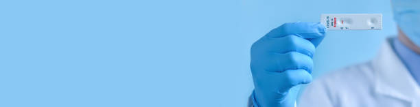 un medico che indossa una maschera protettiva e guanti mostra un test di laboratorio rapido per il ceppo covid-19 xbb.1.5 kraken variant per rilevare gli anticorpi igm e igg al nuovo coronavirus. risultato negativo. striscione - outdoors kraken flowing flowing water foto e immagini stock