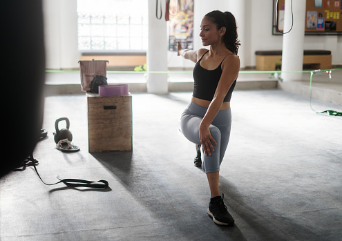 A young latin woman exercising at the gym and resting in step position.