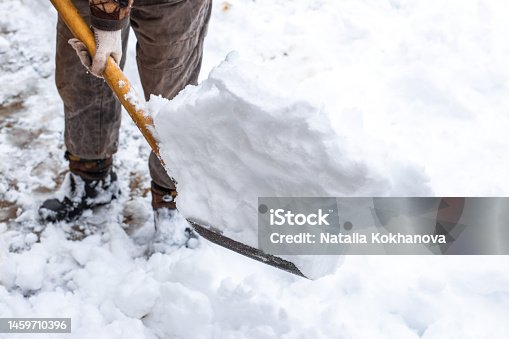 istock A man with a shovel is shoveling snow in the street in the yard of a house. Snow drifts on a winter day. Bad weather and precipitation 1459710396