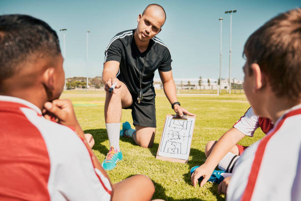 istock Soccer team, children and coach with clipboard while talking workout plan, training and tactics on soccer field outdoor for fitness, competition and sport. Man talking to football group planning game 1459710676
