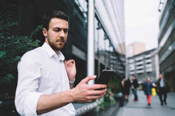istock Elegant manager messaging on smartphone from street 1459719515