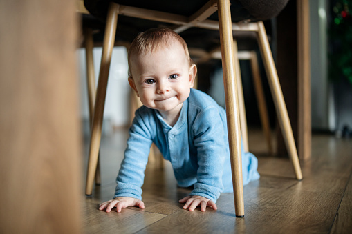 Cute baby boy who just learned to crawl is crawling around the house.