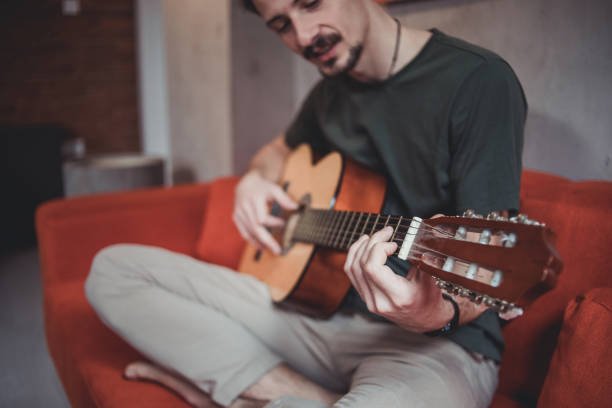 istock A young man sits on a sofa and plays the guitar in his spare time 1459728543