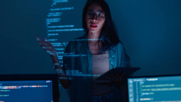 istock Young Asian woman software developers mentor leader manager talking to executive team analyzing source code in office at night. 1459731741