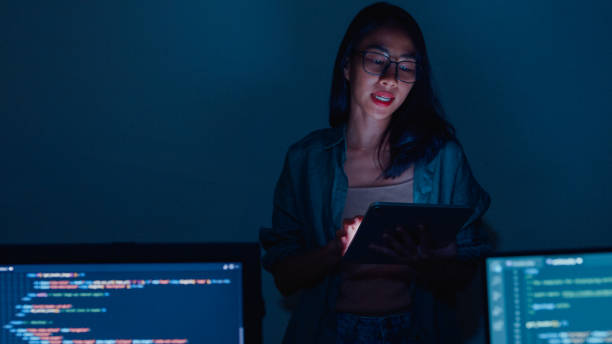 istock Young Asian woman software developers mentor leader manager talking to executive team analyzing source code in office at night. 1459731743
