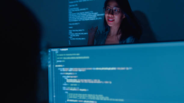 istock Young Asian woman software developers mentor leader manager talking to executive team analyzing source code in office at night. 1459731747