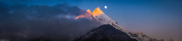 moonrise over golden sunset peak snowy mountain summit panorama himalayas - copy space alpenglow winter mountain range imagens e fotografias de stock