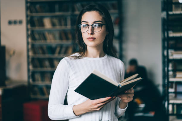istock Smart woman reading book in library 1459734613